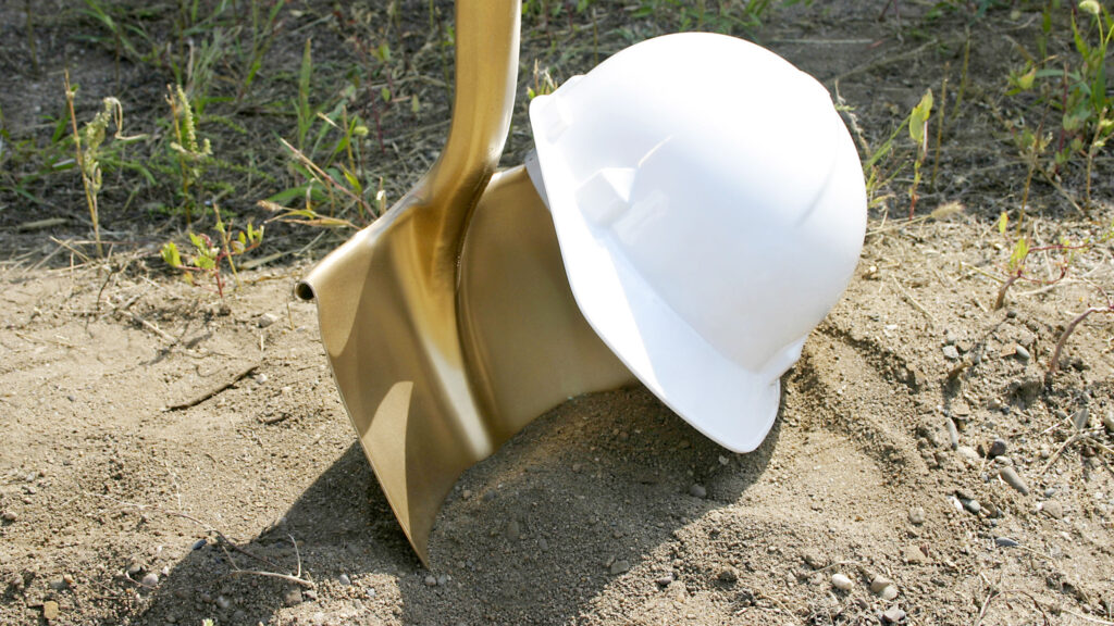Hard hat on a shovel in dirt, construction concept