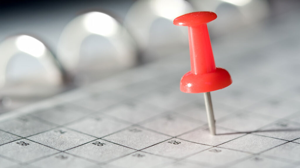 Red pin on calendar date with blurred background